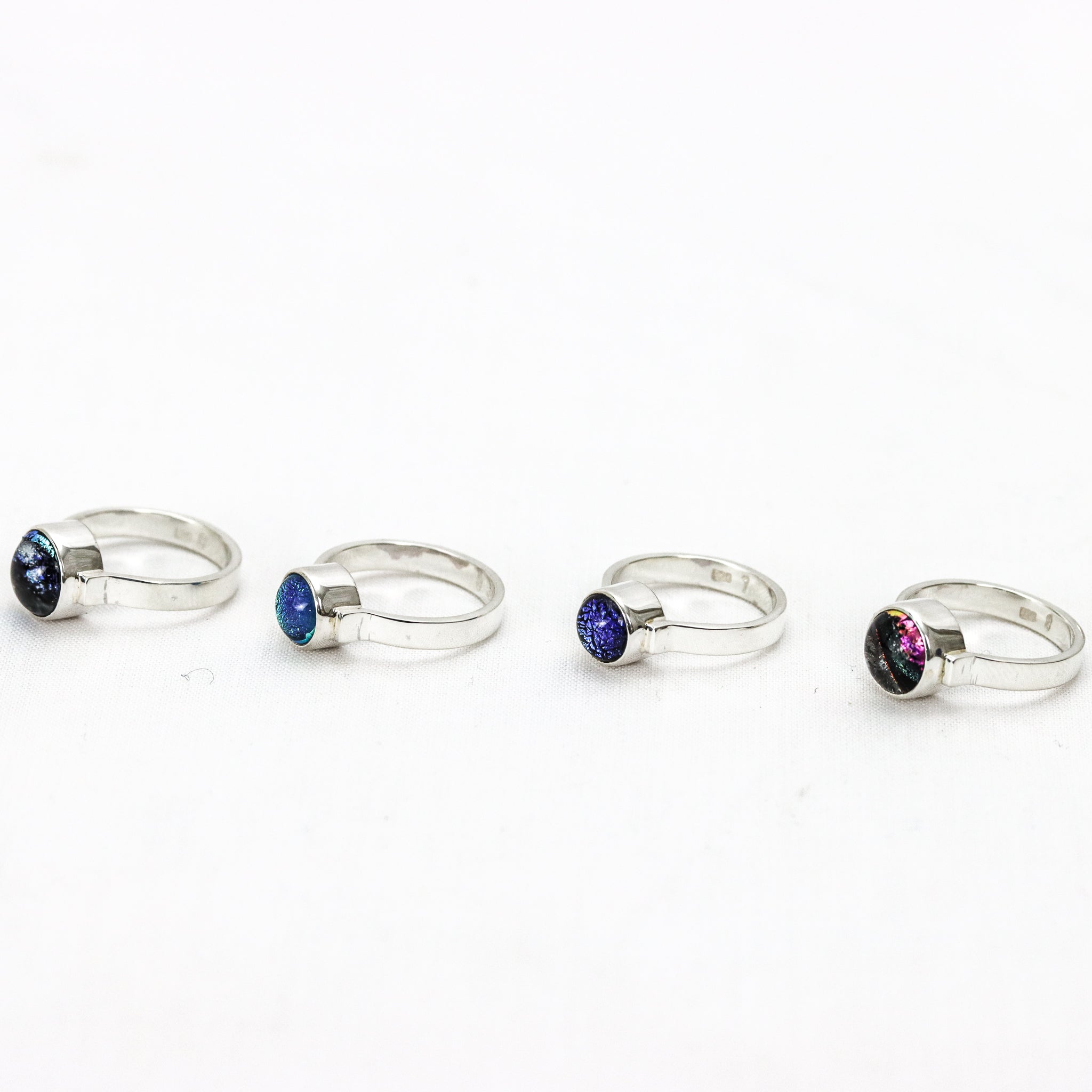 The Ivy Ring collection beautifully presented on a marble block. The colours of lake Hillier, Twilight Deep Water, Twilight beach shallow water and Hellfire Bay, Close up of show the sterling silver band cradling the glass gem and bezel finish.
