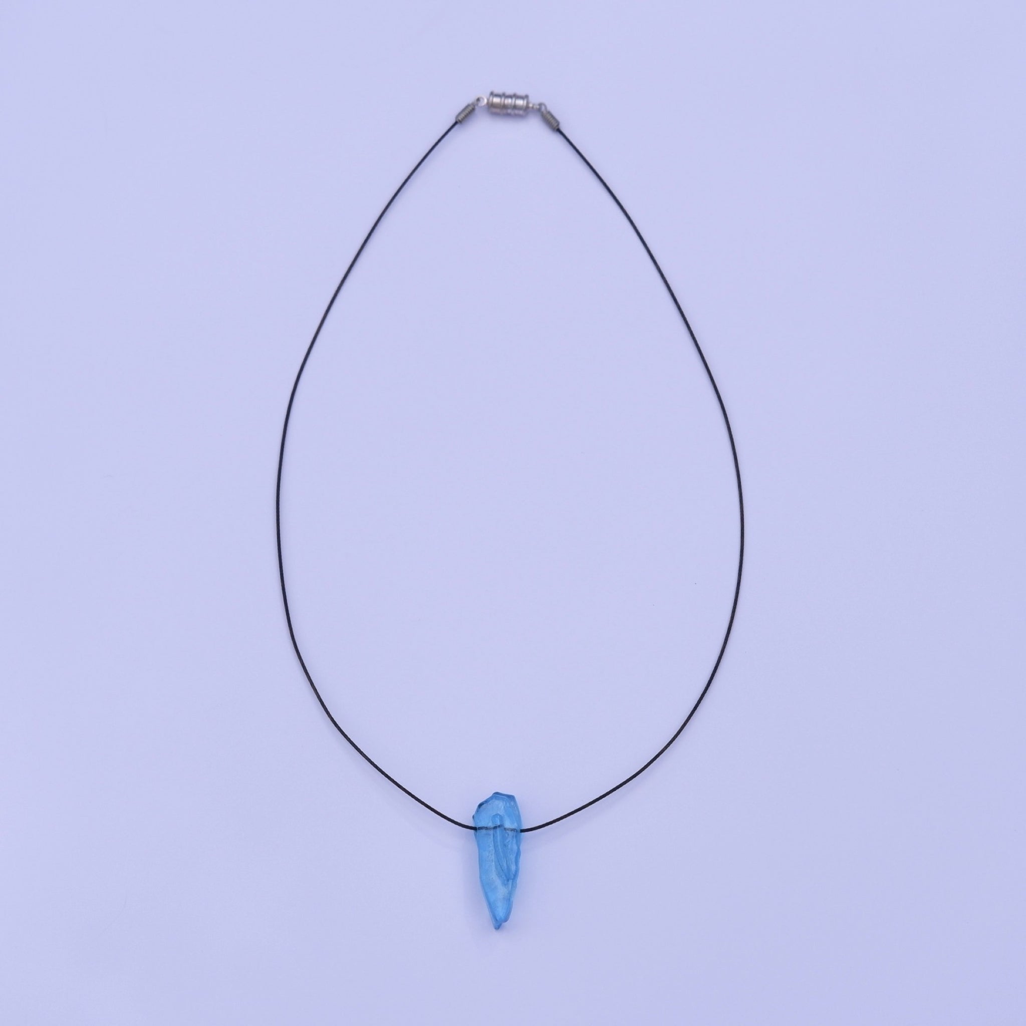 A delicate black stainless steel thread necklace featuring a single light blue teardrop styled glass pendant, displayed against a solid light coloured background.