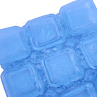 A close-up of a translucent sapphire blue glass bowl with square elements and organic frit, shown on a plain white background